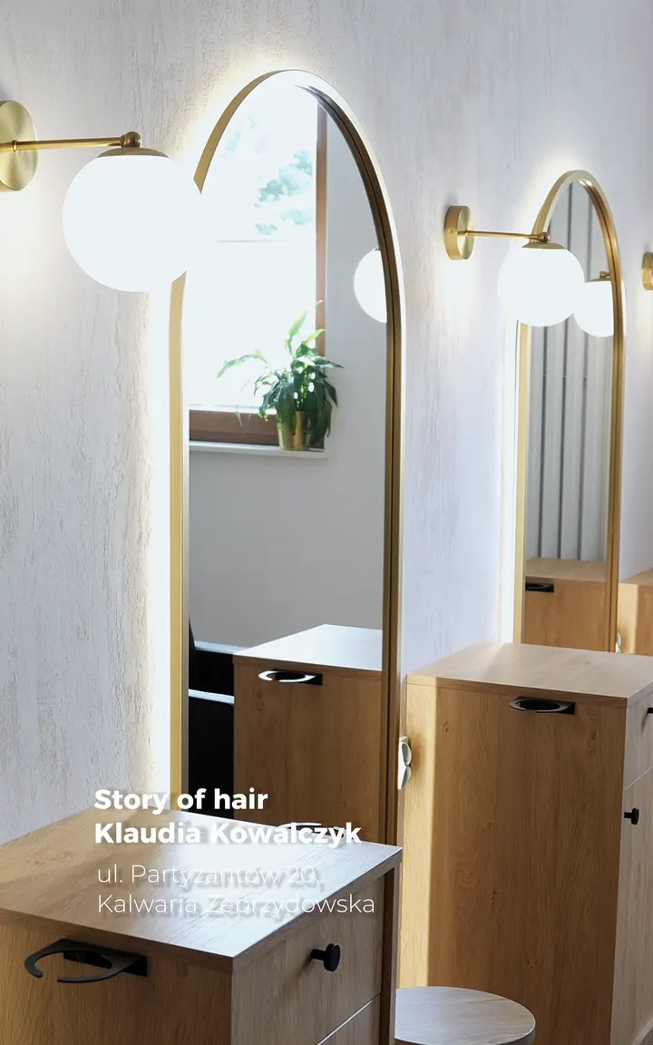 Wnętrze salonu Story of Hair: lustra w złotych ramach w kształcie łuku