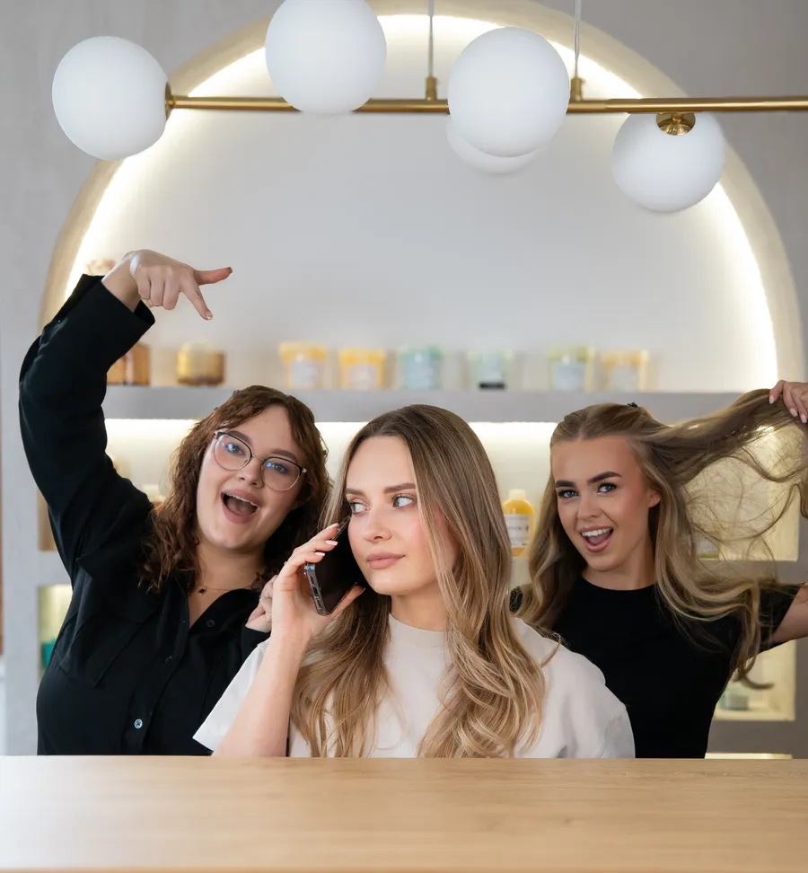 Zespół Story of Hair na wesoło: Klaudia rozmawia przez telefon, a Aleksandra i Tatiana z uśmiechem wskazują na nią
